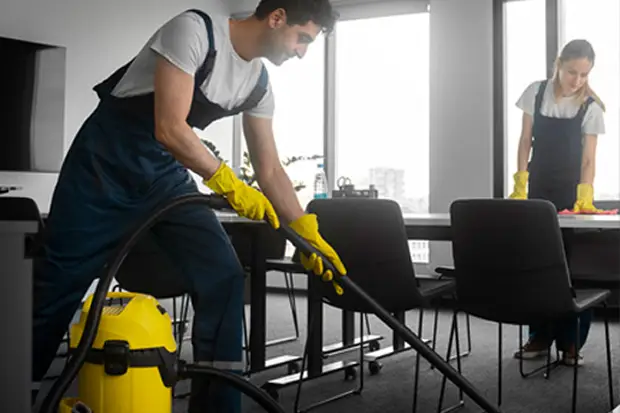 a man in an apron and gloves vacuuming a chair
